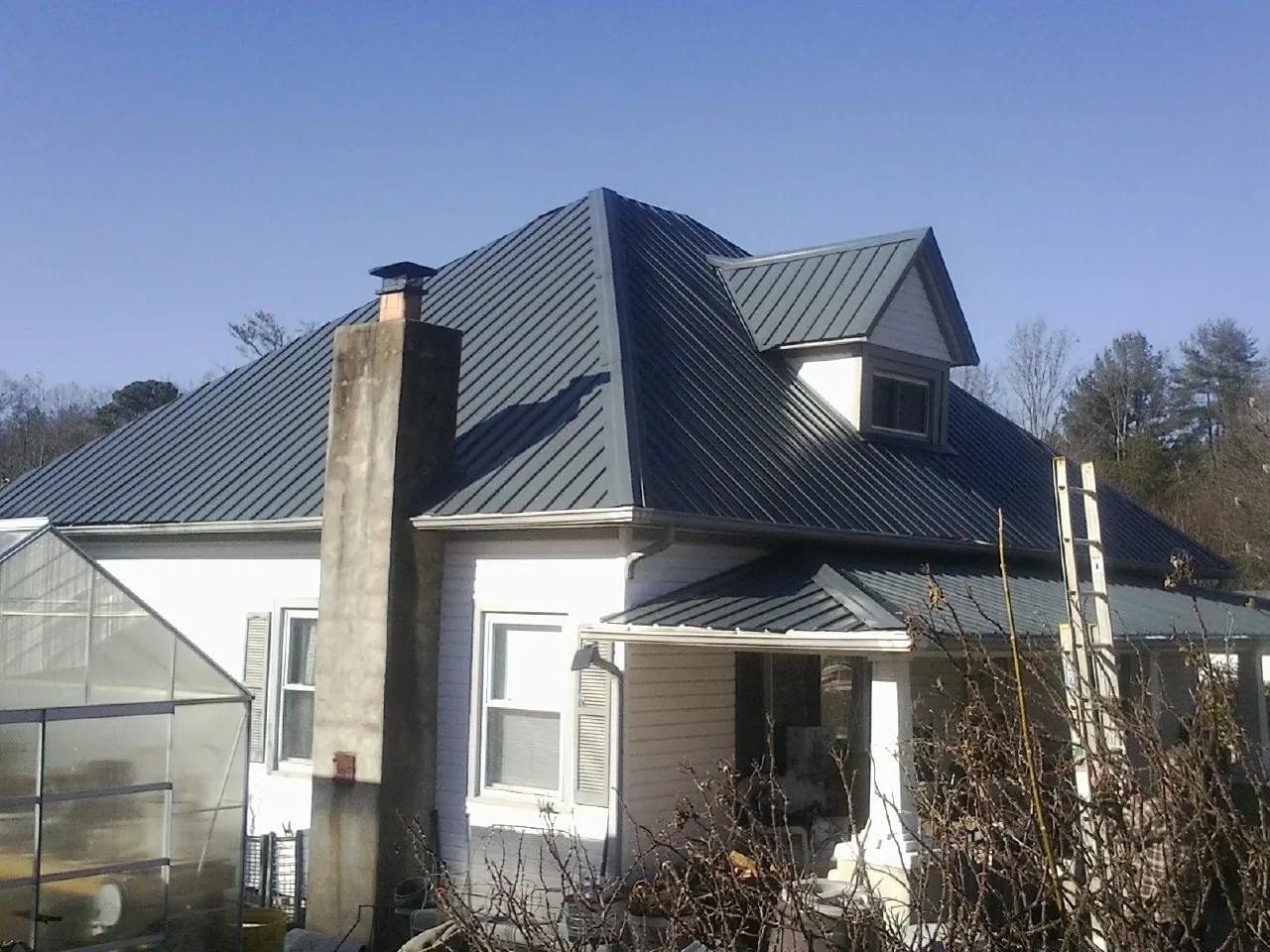 Dark blue standing seam metal roof on a white farmhouse with dormer — Slate & Tile Roof Repair by Roofing Brothers in Hatfield