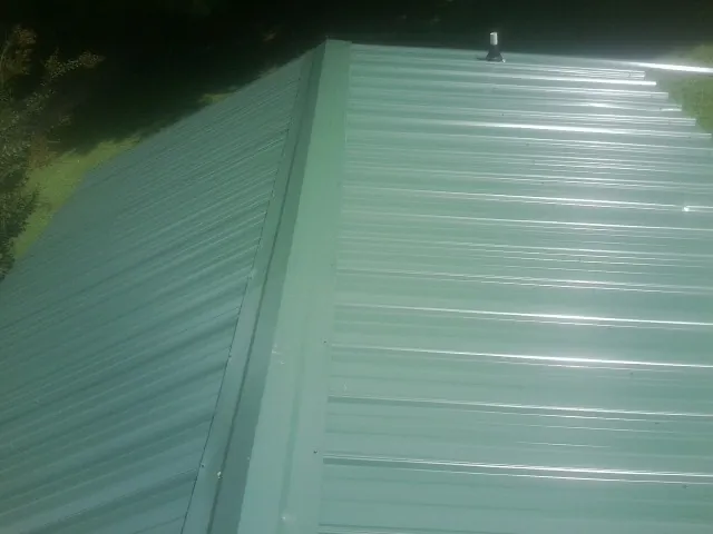 New green metal panels meeting at the ridge of a roof — Flat Roof Repair work by our crew in Hatfield
