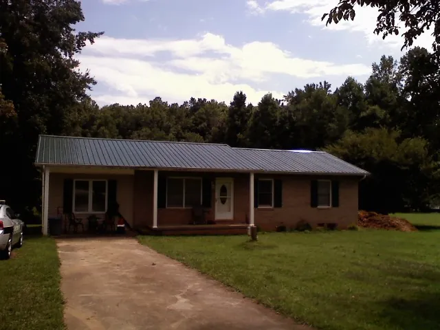 Dark green metal roof on a brick ranch with a covered porch in Hatfield