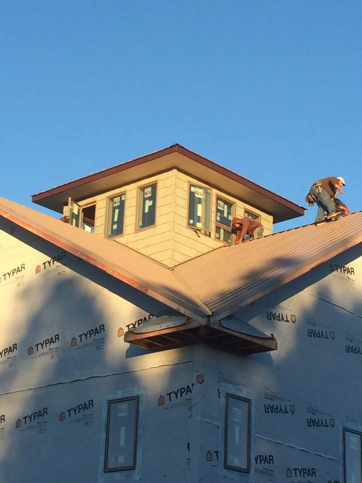 Roofers working around a rooftop cupola on a new metal roof at sunset — Roof Waterproofing in Hatfield by Roofing Brothers